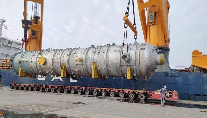 Process column on modular transporters beneath a heavy lift vessel's cranes