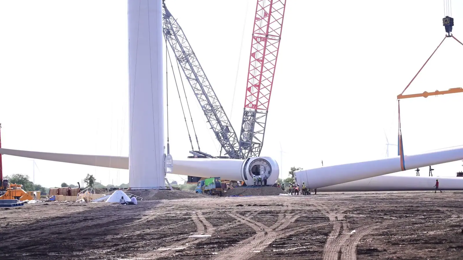 Crawler cranes lifting a wind turbine blade at a wind farm