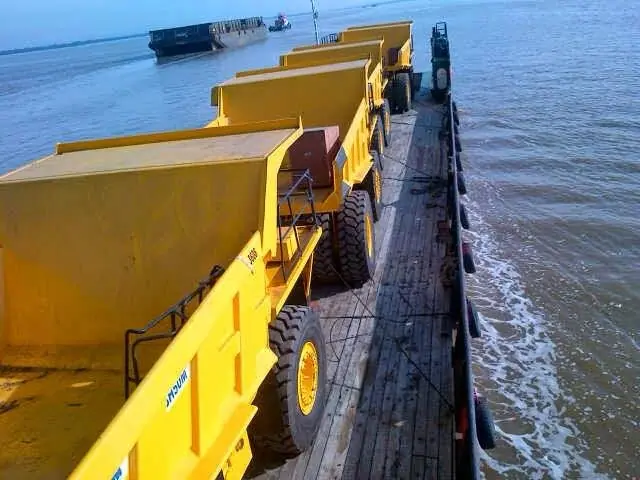 Mining dump trucks on a barge under way
